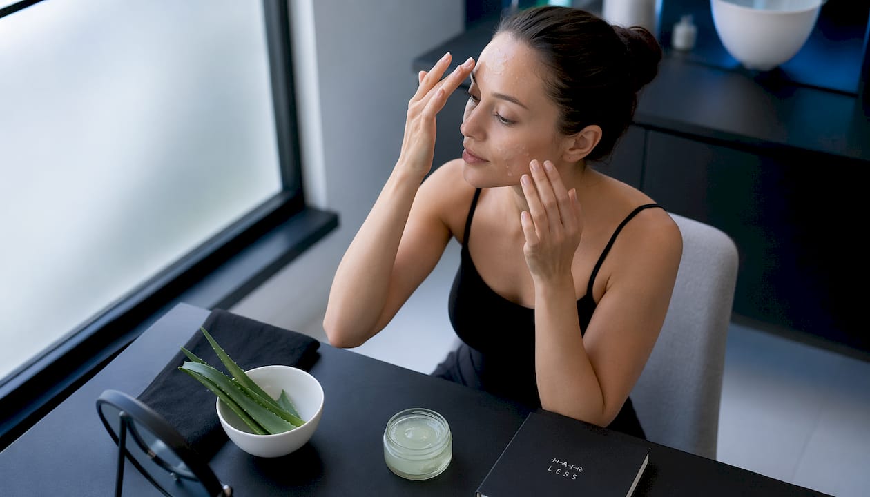Žena si po epilácii tváre nanáša upokojujúci gél z aloe vera.